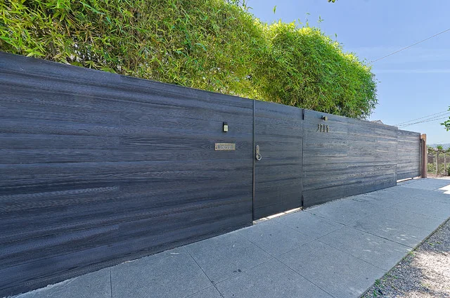 Completed black Shou Sugi Ban boundary fence beside a landscaped pavement