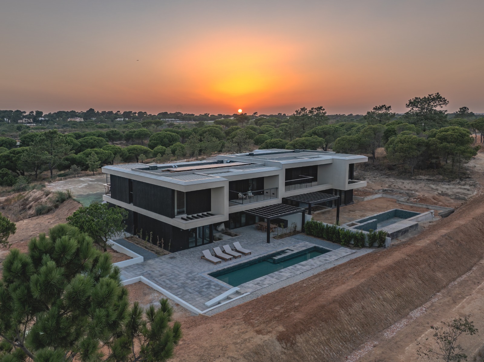 Completed modern residence with black Shou Sugi Ban charred timber cladding and pool terrace at sunset